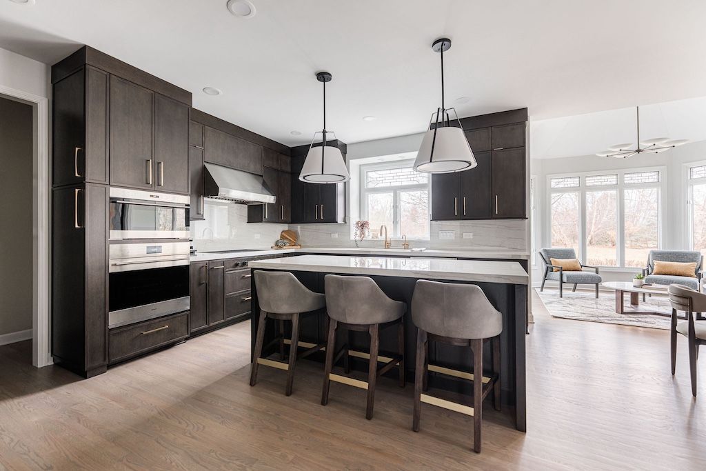 Modern kitchen with dark cabinetry, island with bar stools, and pendant lights.