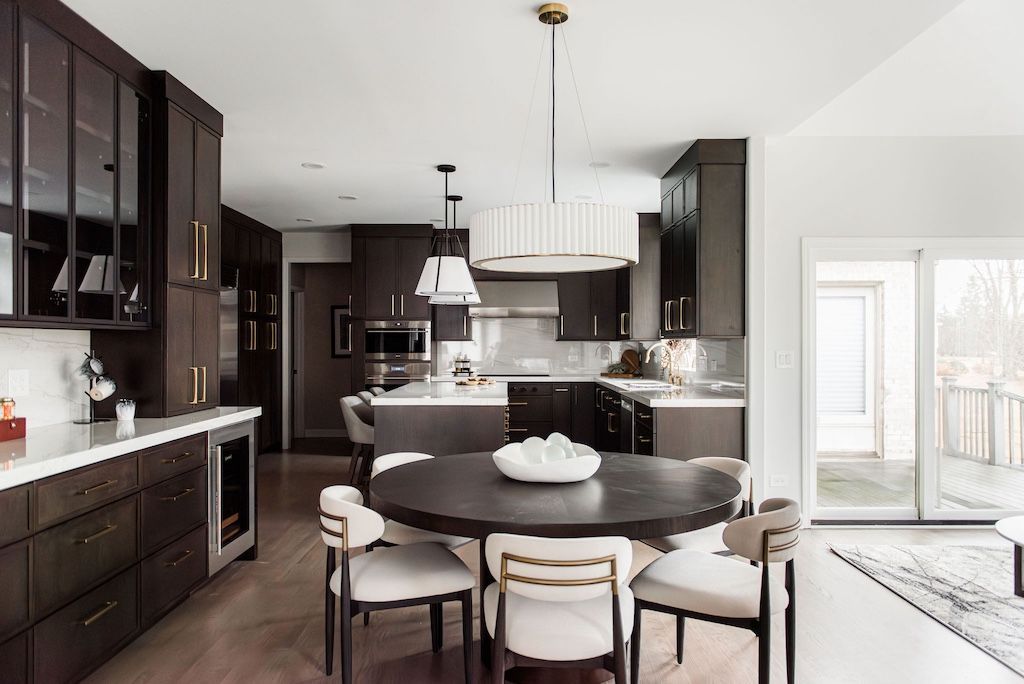 Modern kitchen with dark cabinetry, round dining table, and white chairs.