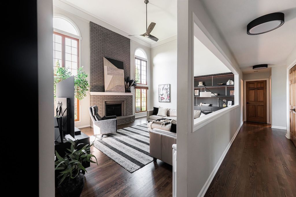 Living room with dark wood floors, fireplace, high arched windows, and a black and white striped rug.