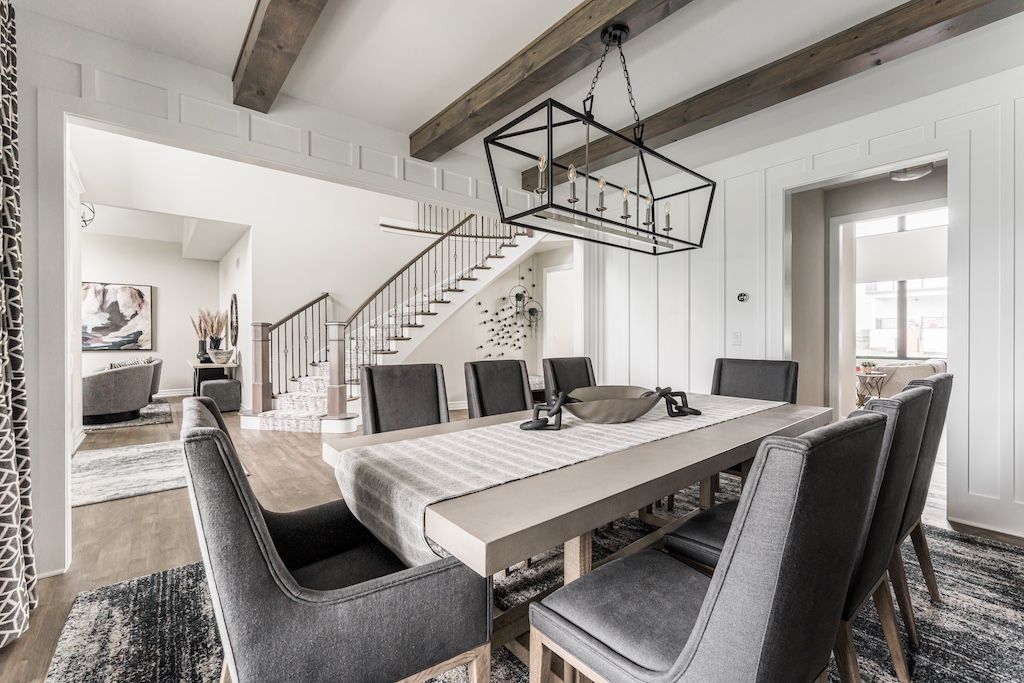 Elegant dining room with gray chairs, a light wood table, and a black chandelier.