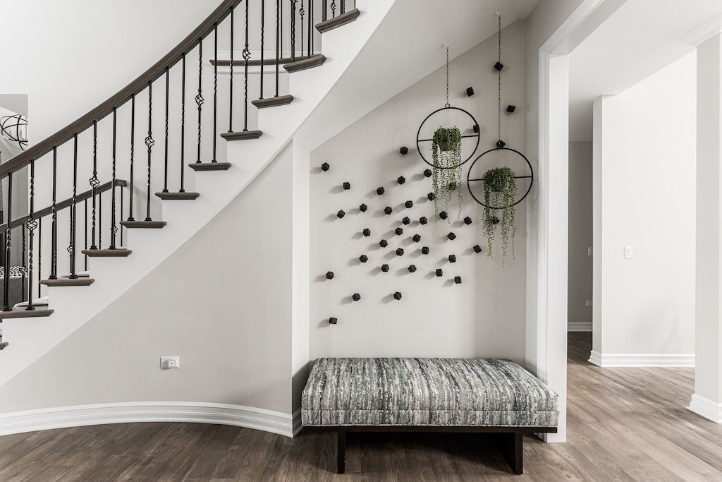 Staircase with bench under it, wall decor with hanging plants.