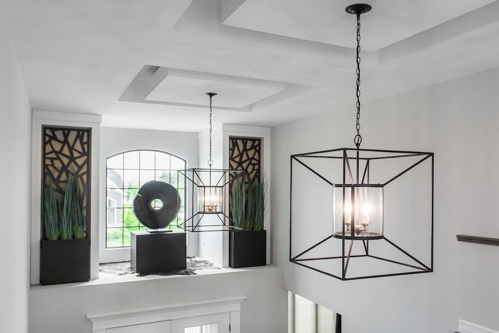 Modern entryway with large black square pendant light and decorative accents.