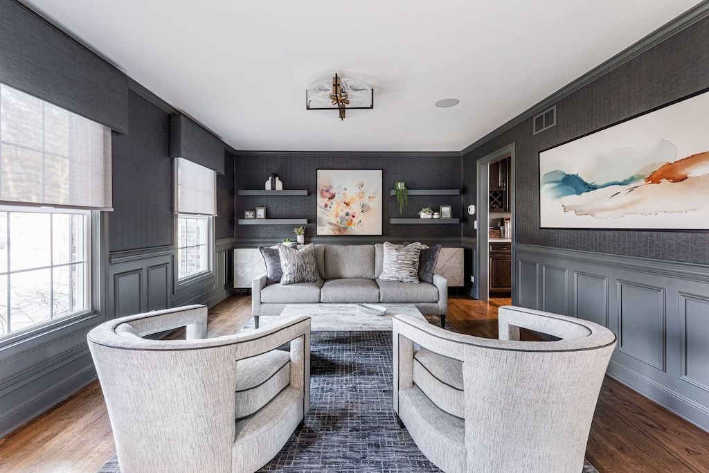 Living room with gray walls, two white armchairs, a gray sofa, and abstract art.