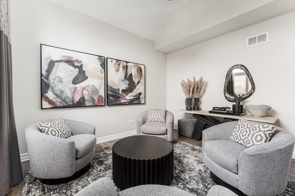 Living room with gray swivel chairs, round coffee table, abstract art, and console table with mirror.