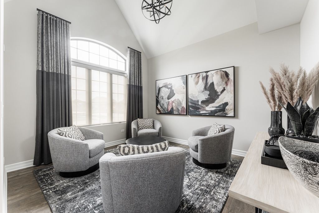 Gray living room with four fuzzy swivel chairs, a large window, and abstract art.