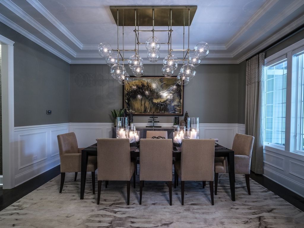 Dining room with chandelier, dark table, beige chairs, and artwork.