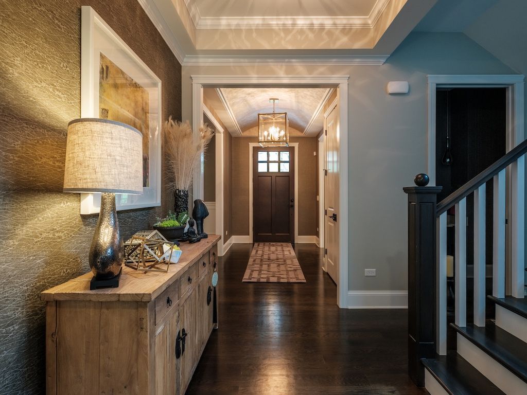Hallway with wood floors, a wooden console, a lamp, and a doorway.