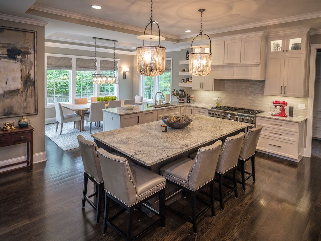Spacious modern kitchen with island seating, pendant lights, and connected dining area with large windows.