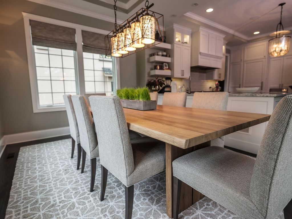 Dining room with wooden table, gray chairs, patterned rug, and decorative light fixture.