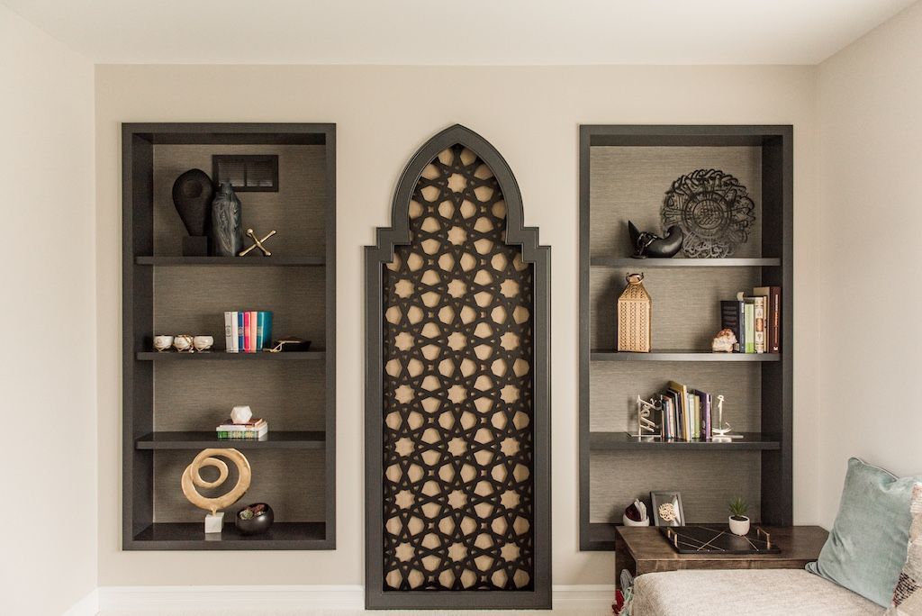 Built-in shelves with decorative items flanking a central panel with an arched Islamic-inspired design.
