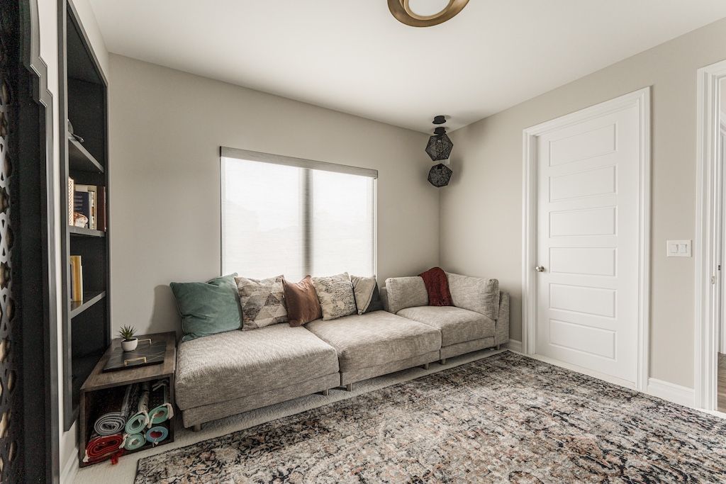 A cozy living room with a large sofa, bookshelves, and a patterned rug.