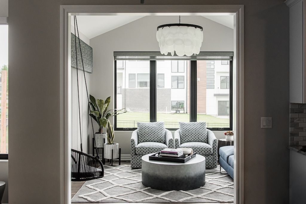 Living room with patterned chairs, gray rug, and a feathered chandelier.