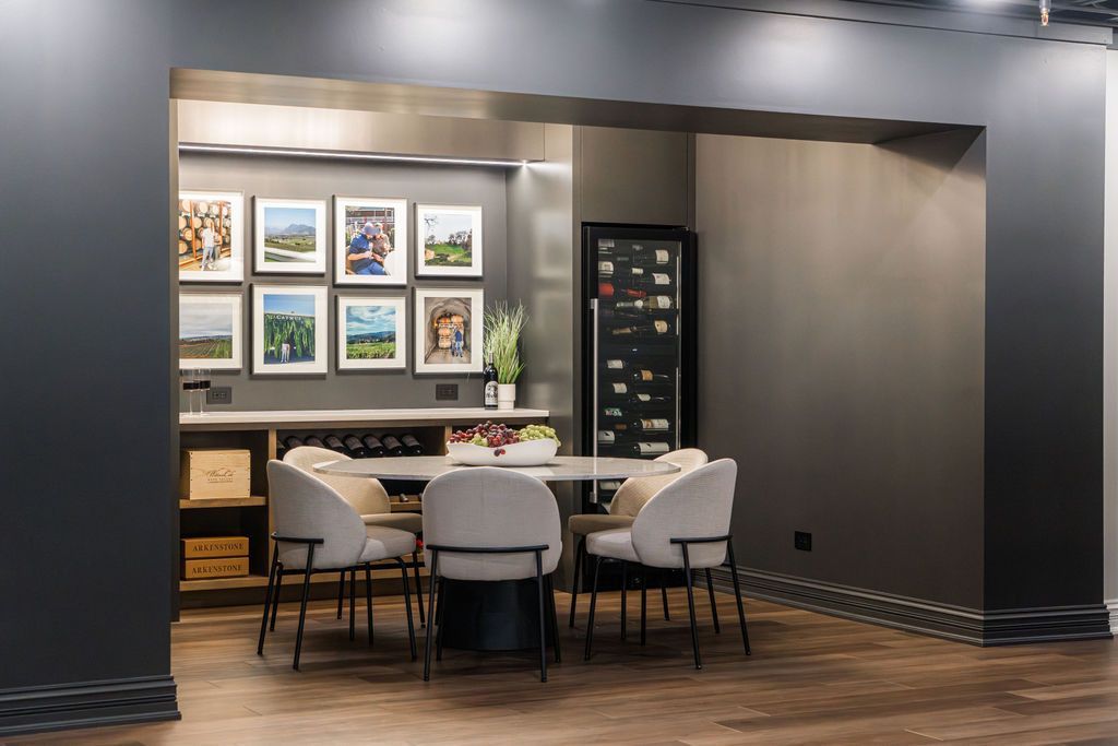 A contemporary dining nook with a round table, four upholstered chairs, and a gallery wall of framed art.