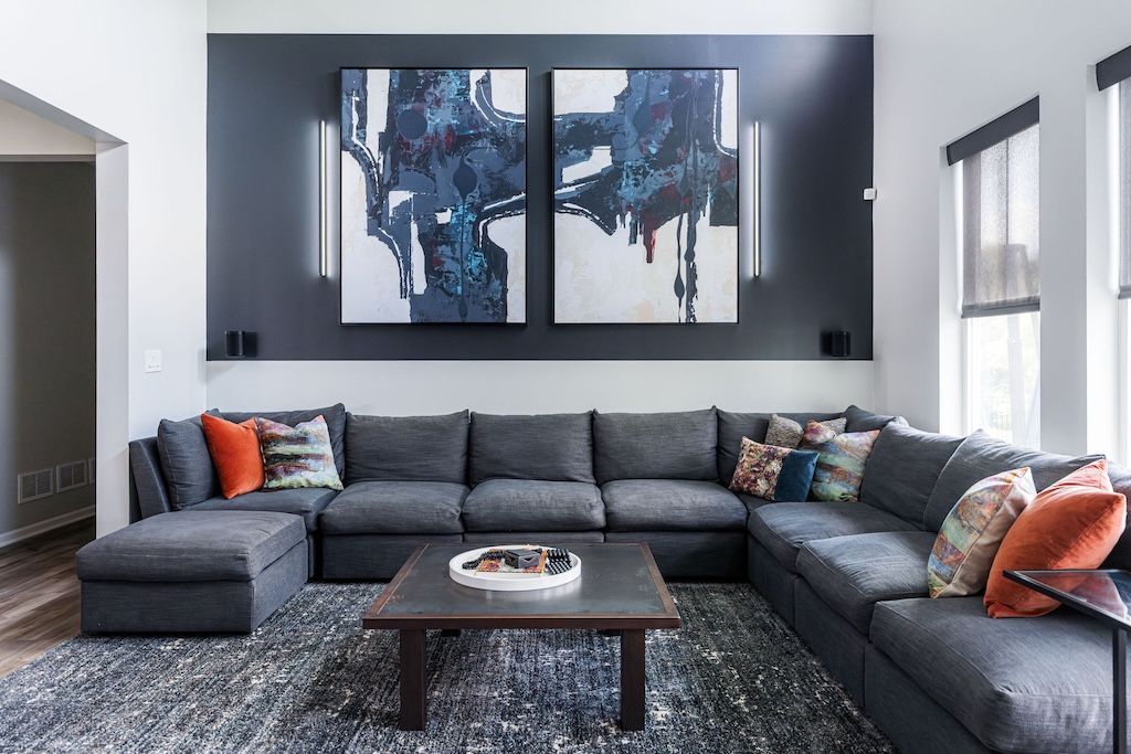 Dark gray sectional sofa in a modern living room with abstract art and a rug.