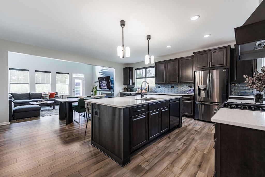 Spacious modern kitchen with dark cabinets, stainless steel appliances, and large island with pendant lights.