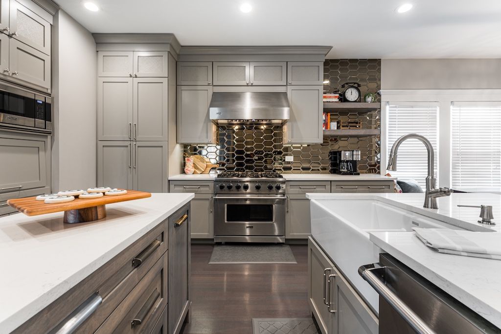 Modern kitchen with gray cabinets, stainless steel appliances, and white countertops.