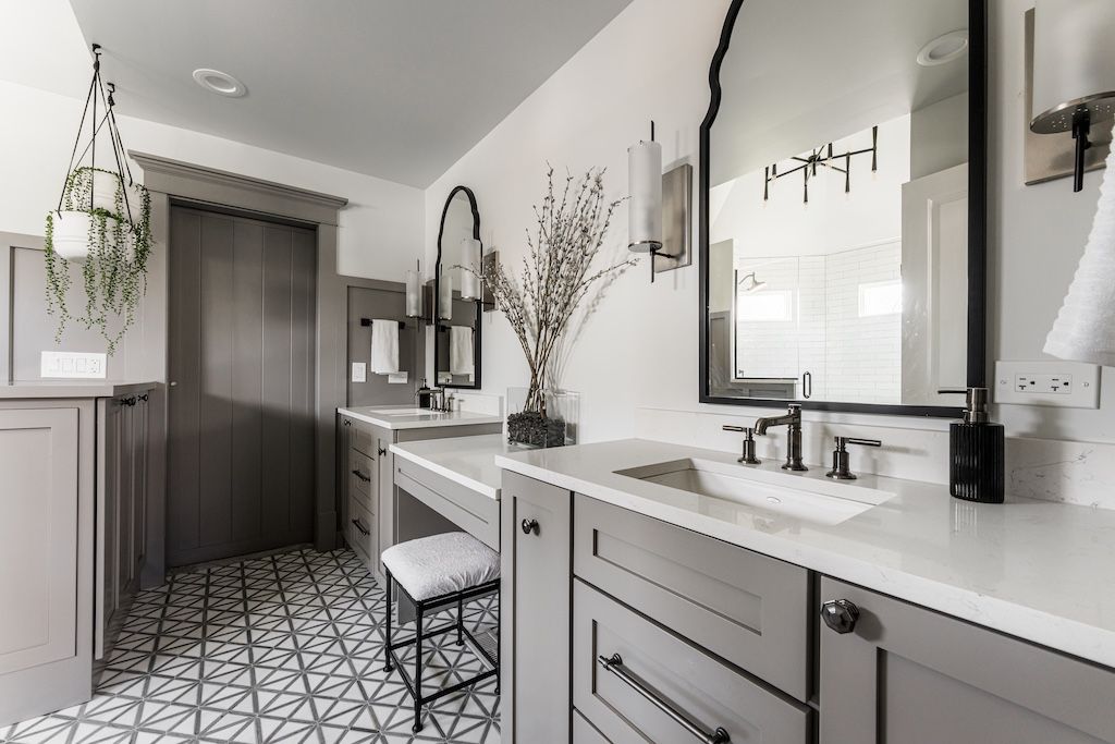 Stylish gray and white bathroom with two sinks, patterned tile floor, and large mirrors.