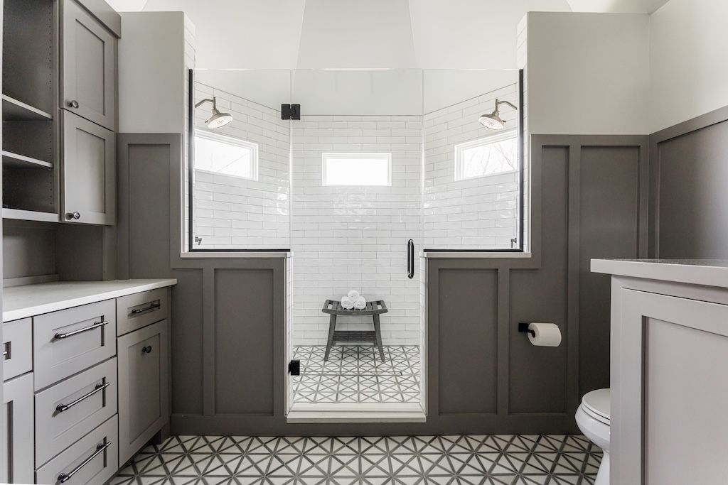 Gray and white bathroom with a walk-in shower, cabinets, patterned floor, and a toilet.