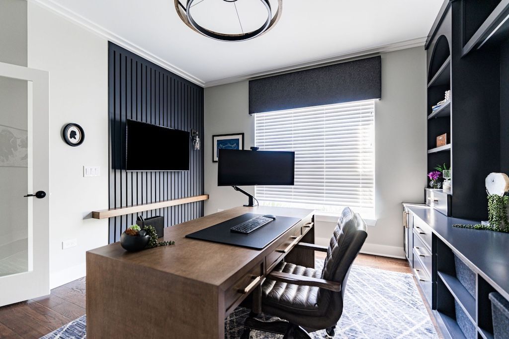 Office with desk, computer, window, and built-in shelves in a modern style with dark blue accent wall.