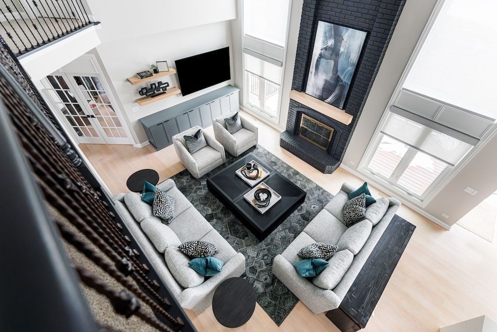 High-angle view of a modern living room with gray sofas, a fireplace, and large windows.