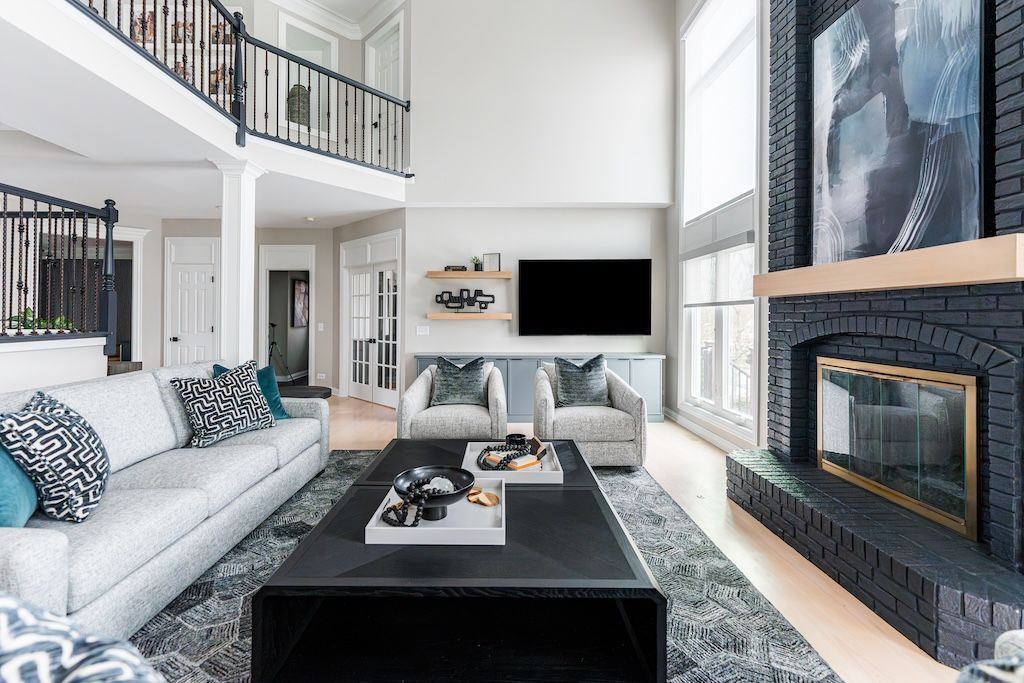 Living room with high ceilings, fireplace, and two-story balcony with gray and blue accents.