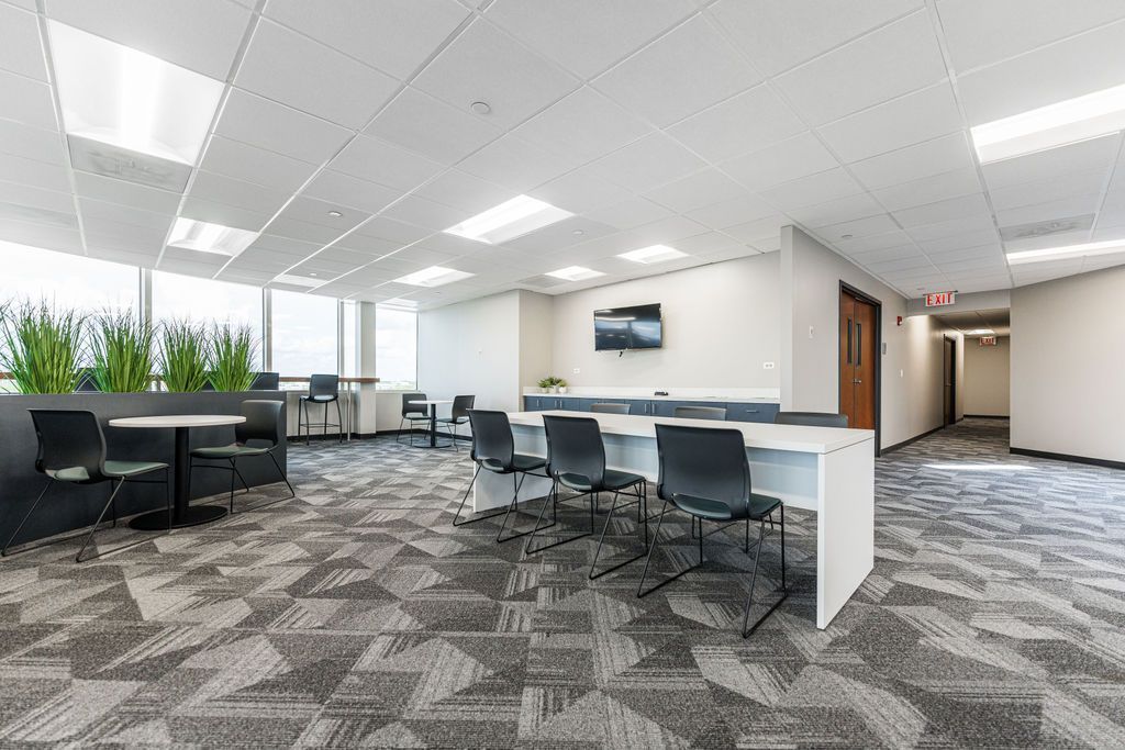 Modern office lounge with seating, long white desk, and patterned carpet.