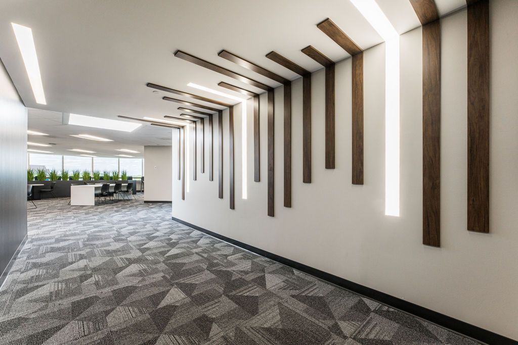 Office hallway with patterned carpet, white walls, and wooden accent beams with integrated lighting.