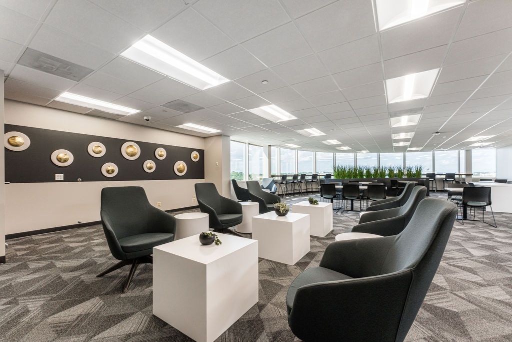 Modern office lounge with black chairs, white cubes, and panoramic windows.