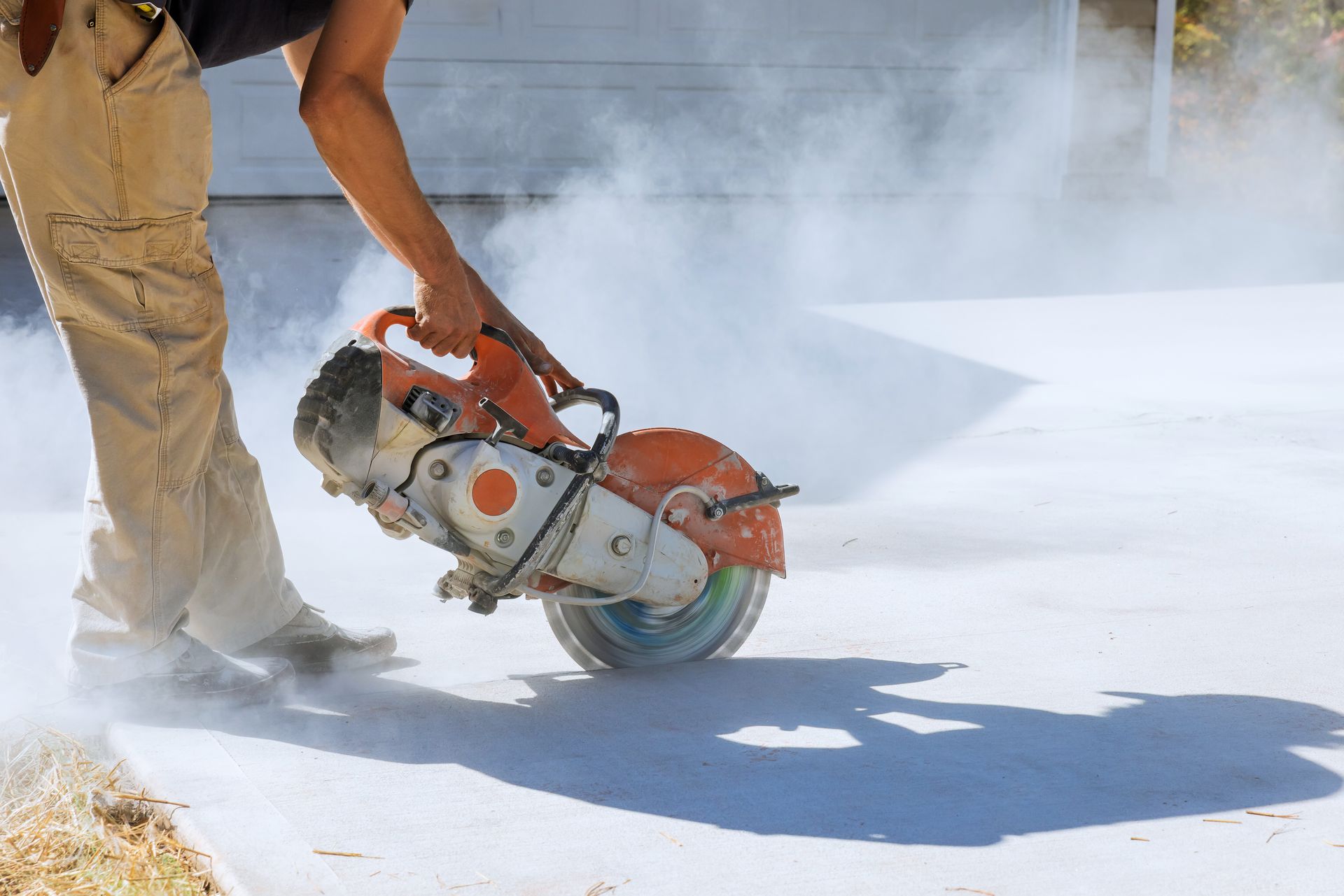 Concrete slab removal with diamond blade saw by construction worker for precise paving demolition.
