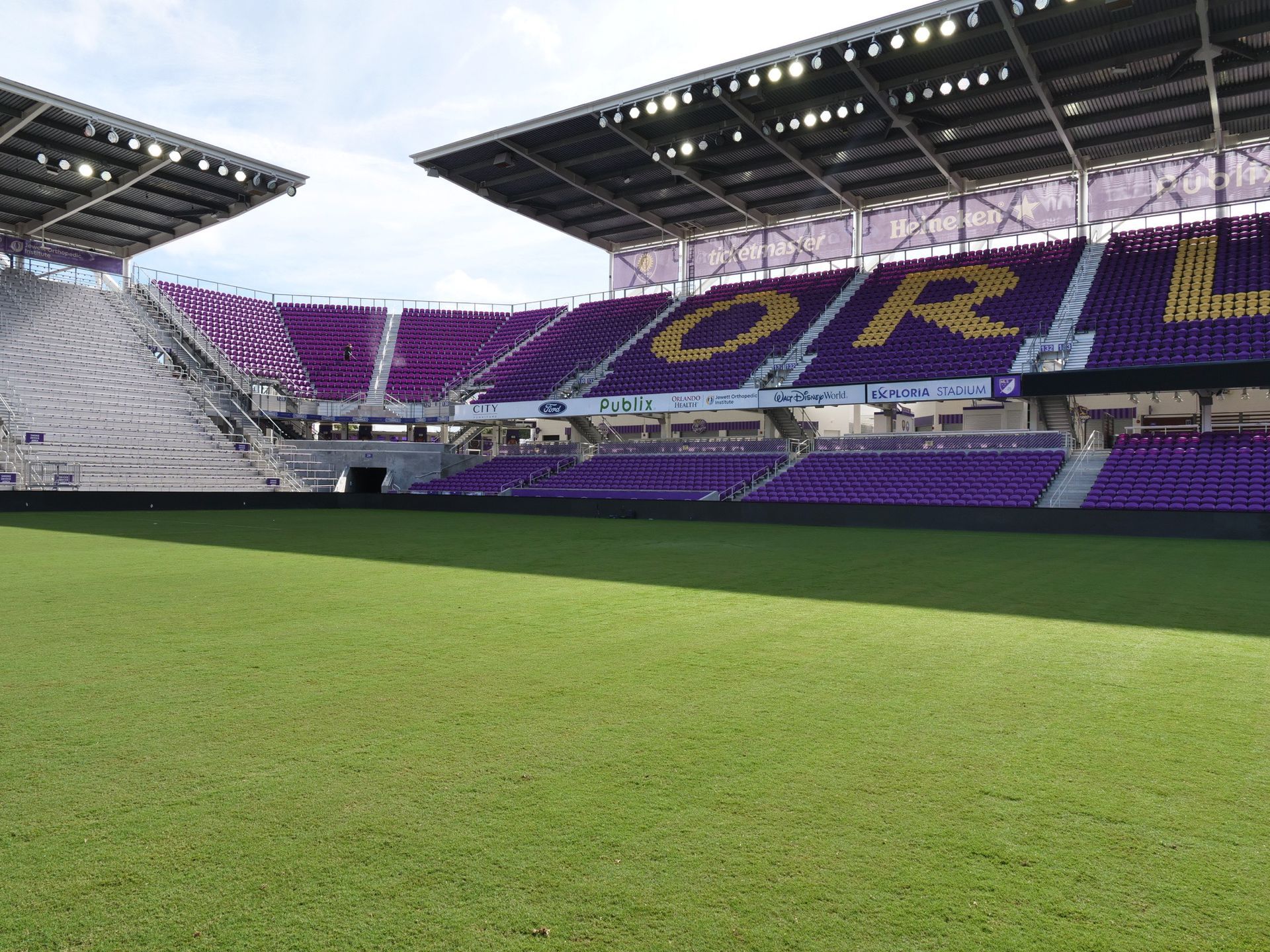 A lush green field with trees in the background and the sun shining through the trees.