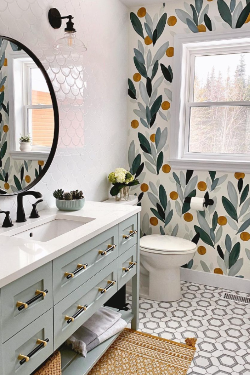 A modern bathroom with light blue vanity, patterned wallpaper, and geometric tile floor.