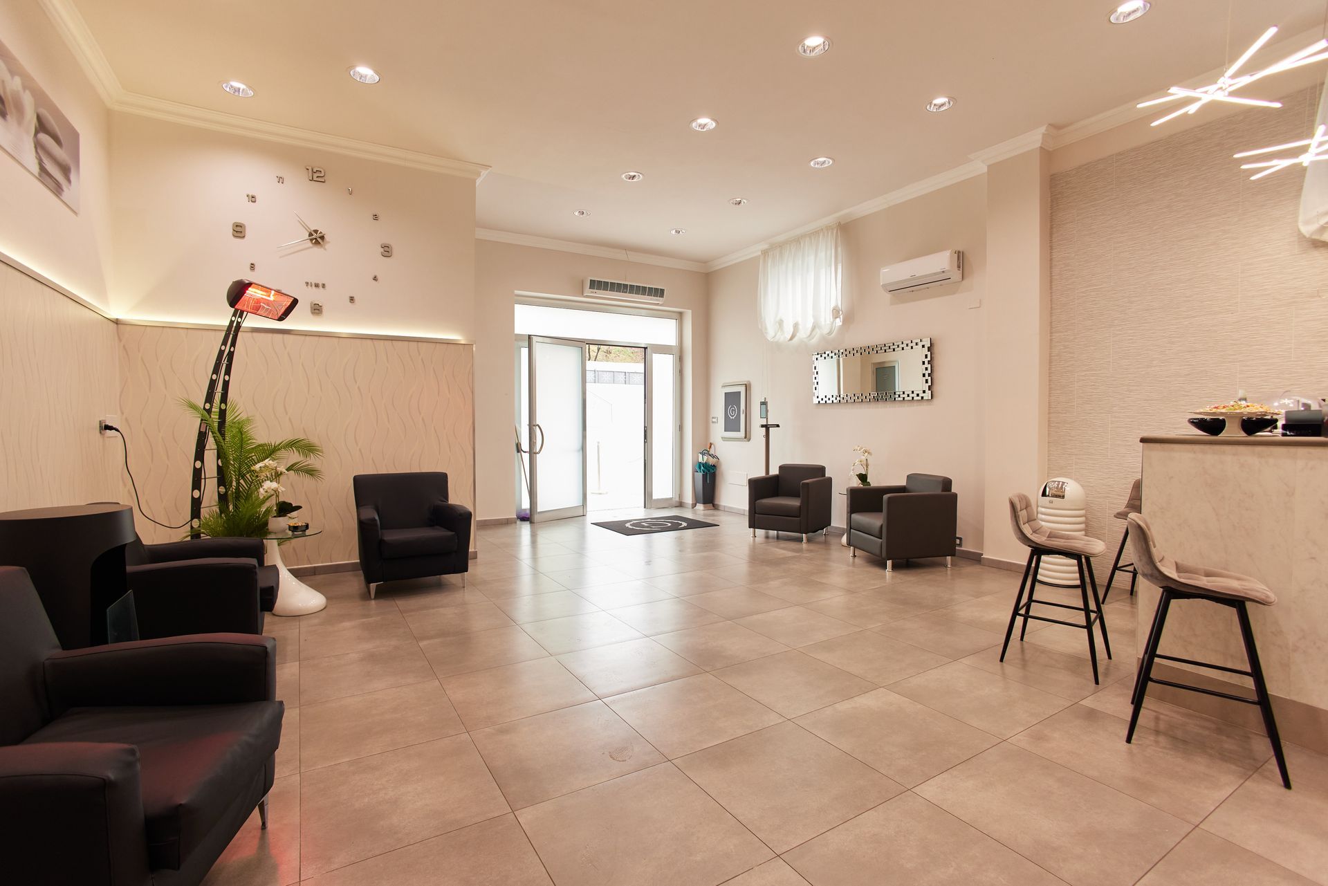 Area reception con posti a sedere, porta aperta ed elementi decorativi.