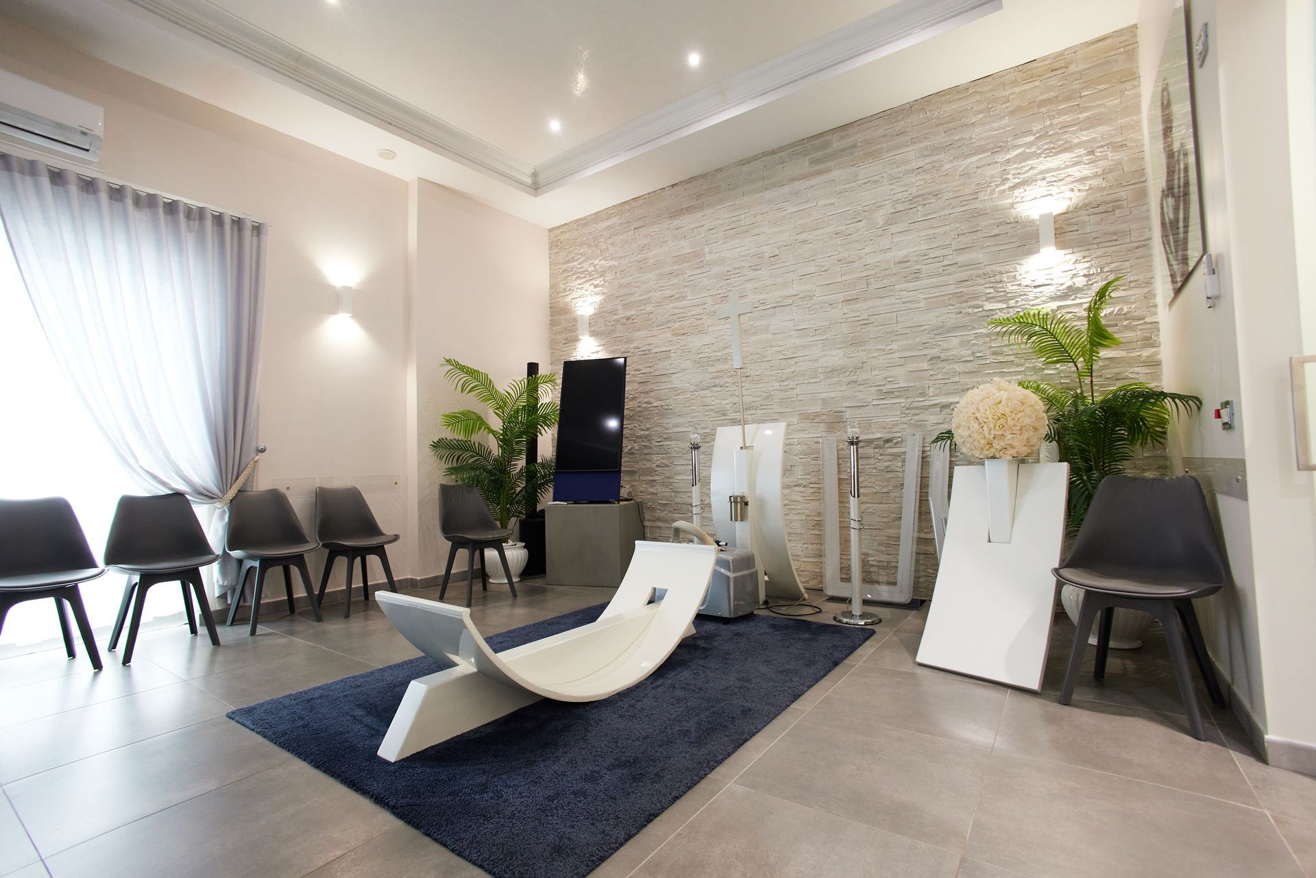 Moderna sala d'attesa con posti a sedere, chaise longue e piante decorative.