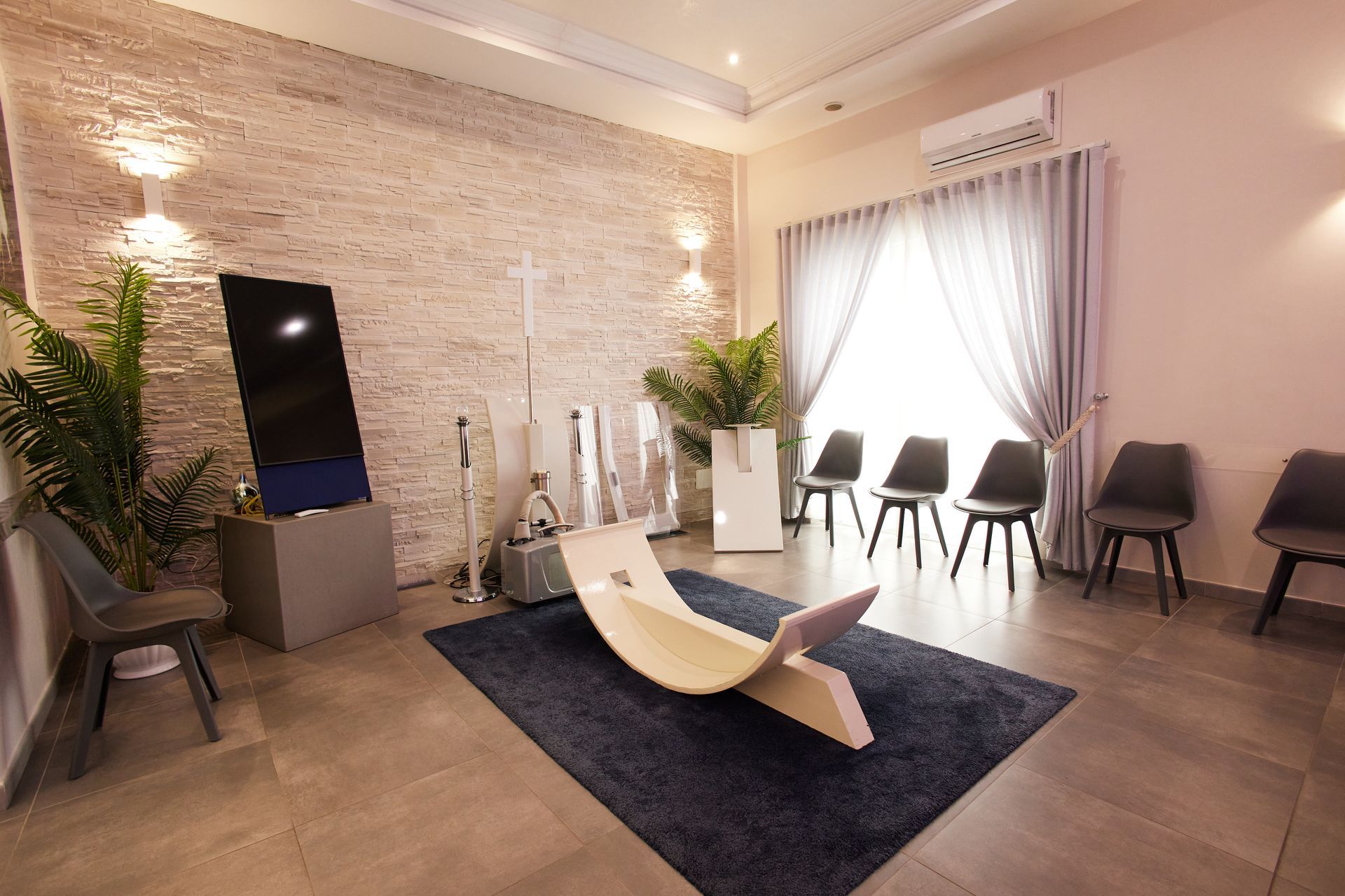 Sala d'attesa con mobili moderni, piante, pareti strutturate e luce naturale.