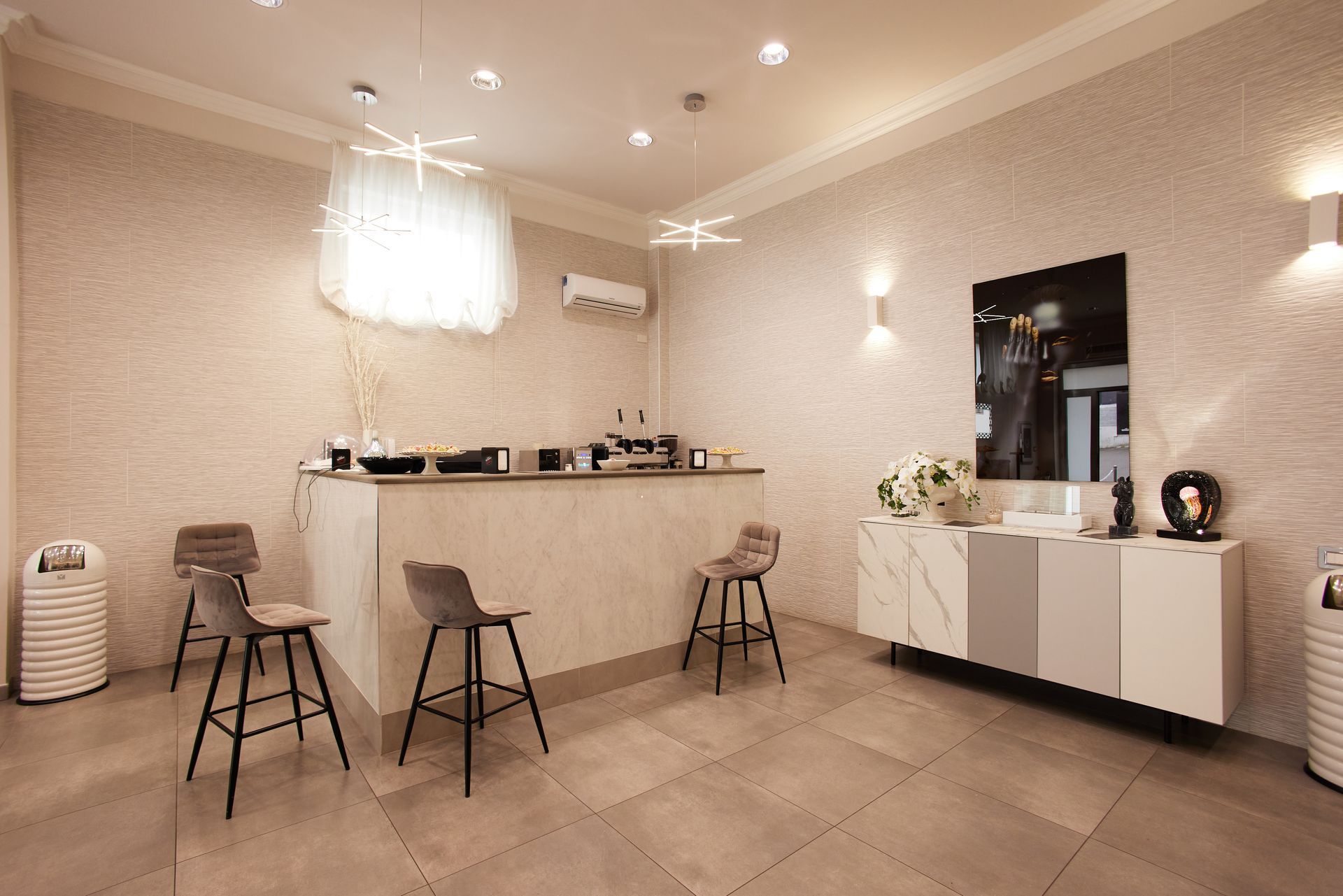 Interno di una gioielleria con posti a sedere al bar, vetrina e illuminazione decorativa.