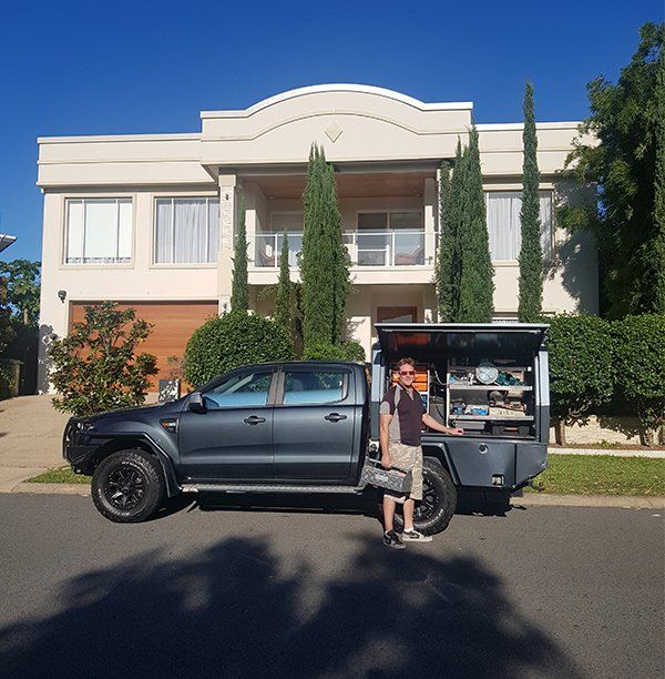 A man is standing next to a pickup truck in front of a house