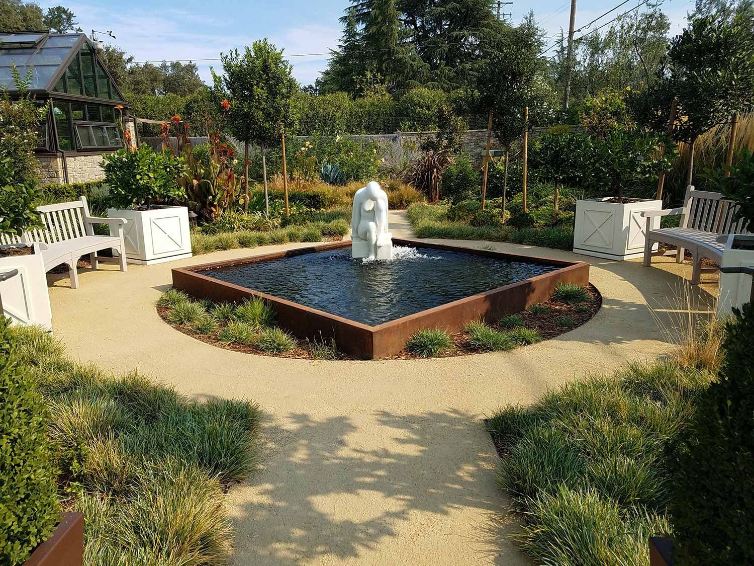 House with landscaped yard, pond with fountain, deck with seating, and green grass.