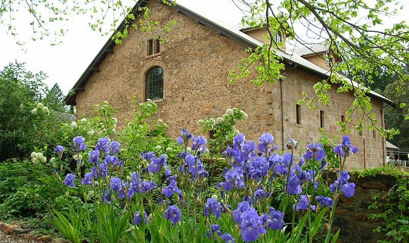 Park with green grass, flower beds, and modern buildings under a sunny sky.