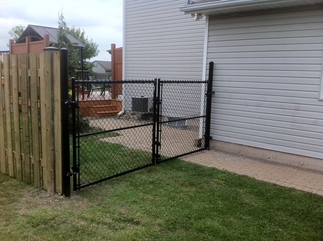 A chain link fence with a wooden fence in front of a house.