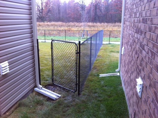 A chain link fence along the side of a house