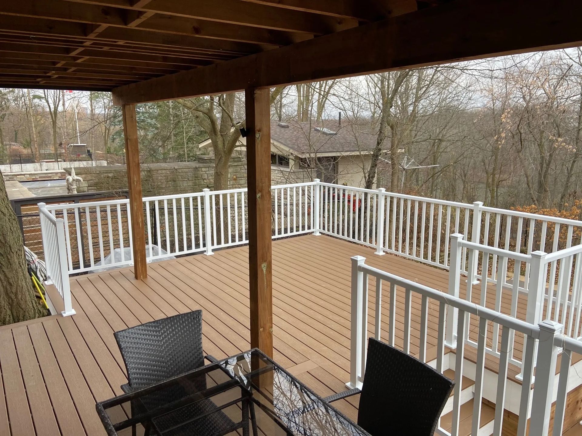 A deck with a table and chairs and a white railing.