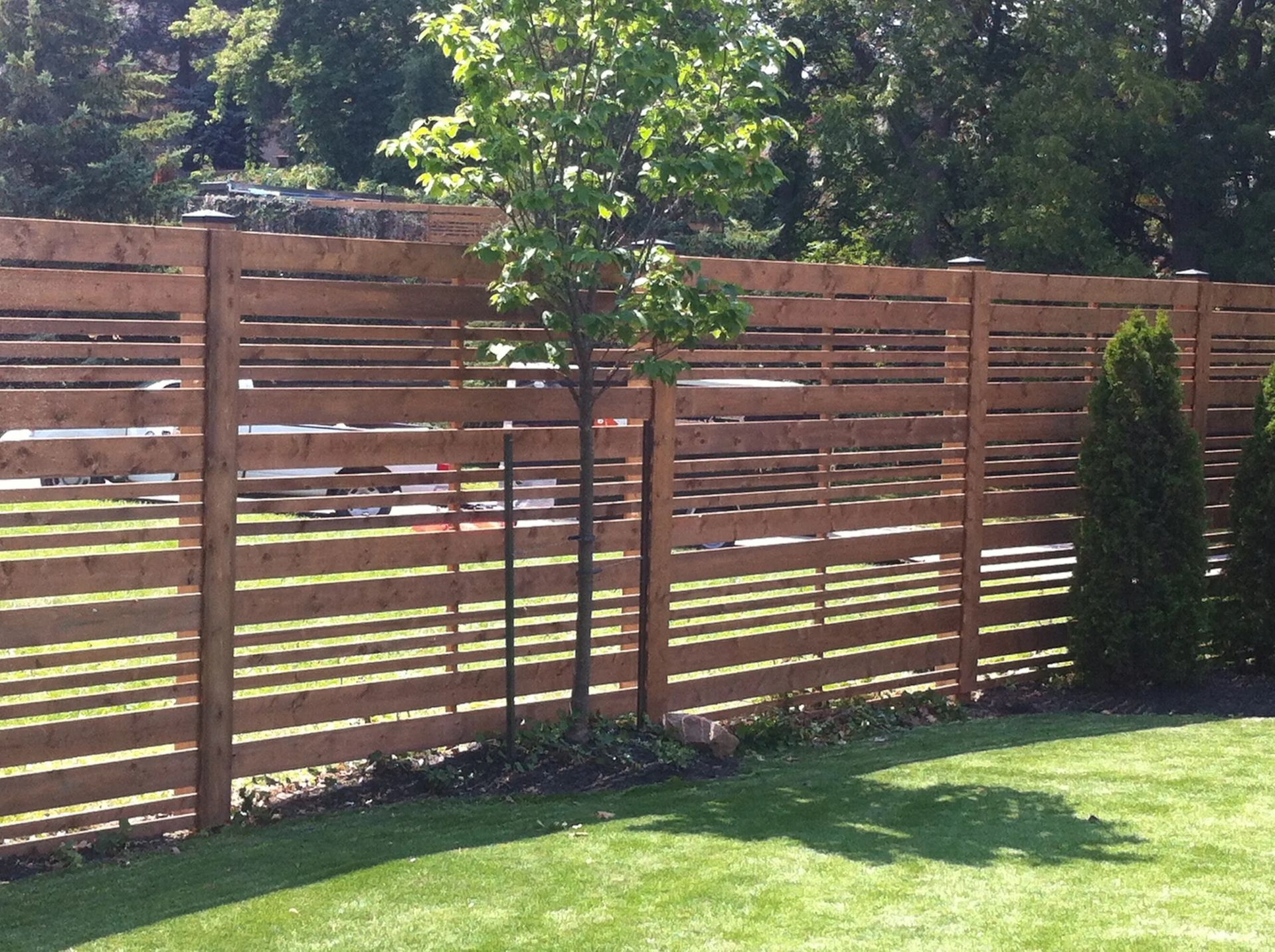 A wooden fence surrounds a lush green yard