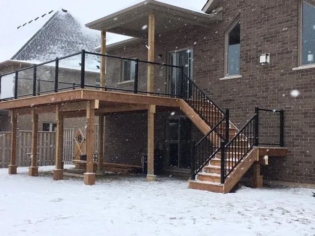 A house with a deck and stairs in the snow