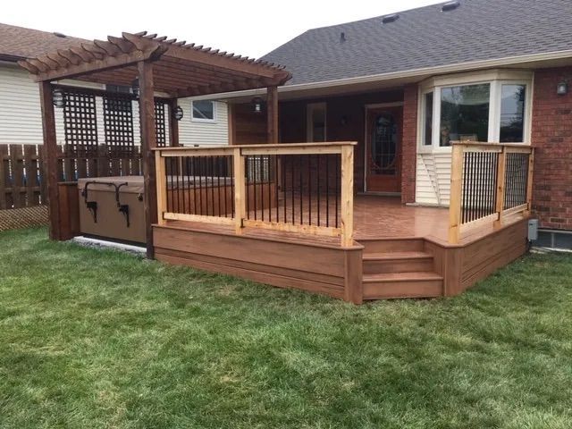 A wooden deck with stairs and a pergola in the backyard of a house.