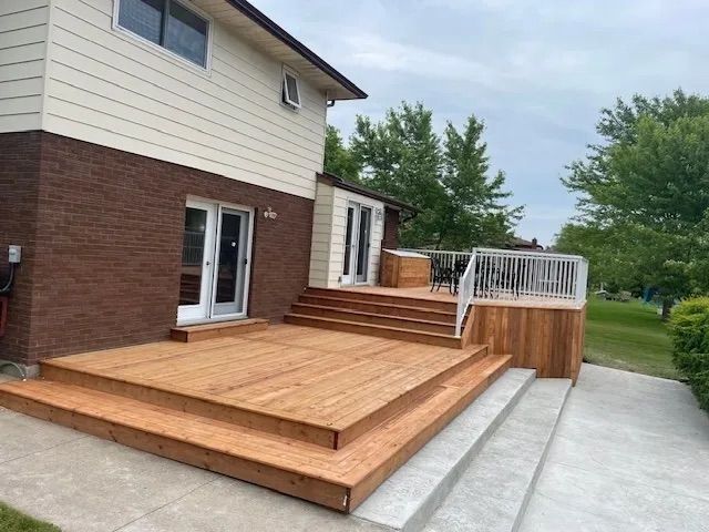 A large wooden deck with stairs is in front of a house.
