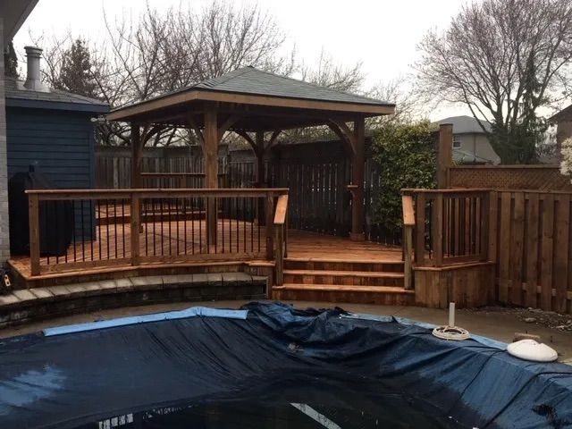 A wooden deck with stairs and a gazebo next to a pool