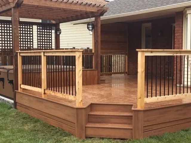 A wooden deck with stairs and a pergola in front of a house.