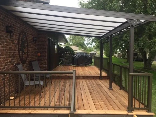 A wooden deck with a canopy over it and chairs.