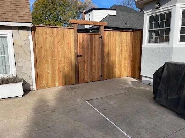 A wooden fence is in the backyard of a house.