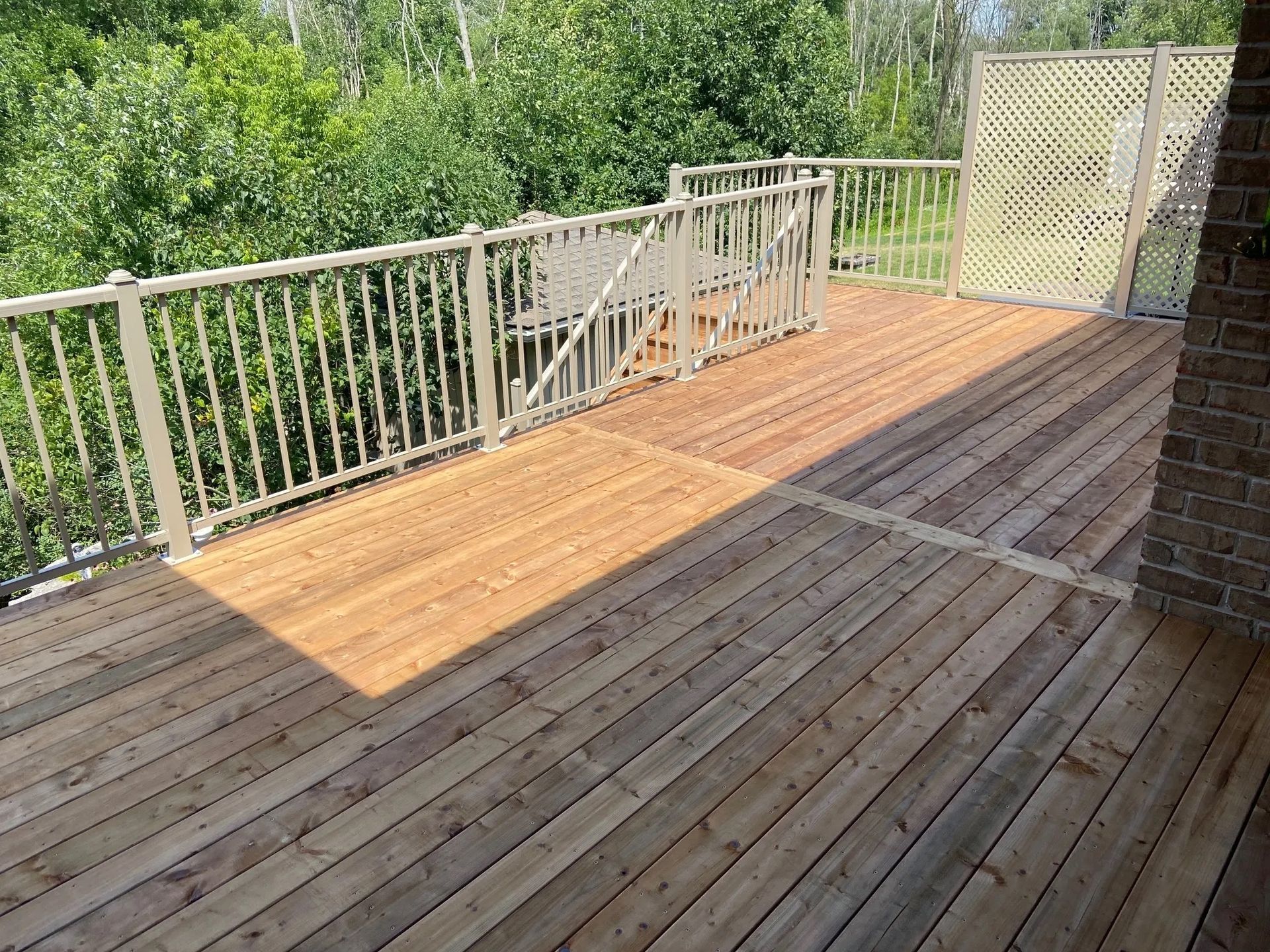 A wooden deck with a metal railing and stairs.
